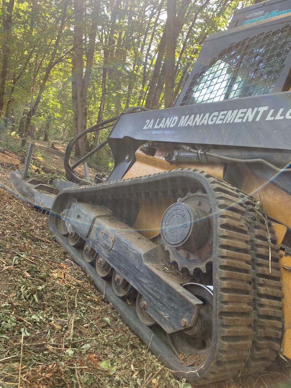 Tracked forestry equipment from 2A Land Management LLC in a wooded area.